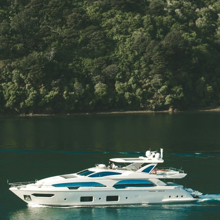 Bootsgutachten Ein elegantes Motorboot schifft ruhig auf glattem Wasser, umgeben von grüner Landschaft.