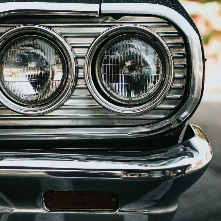 Oldtimerbewertung Nahaufnahme der Frontscheinwerfer eines klassischen Autos mit verchromtem Grill.